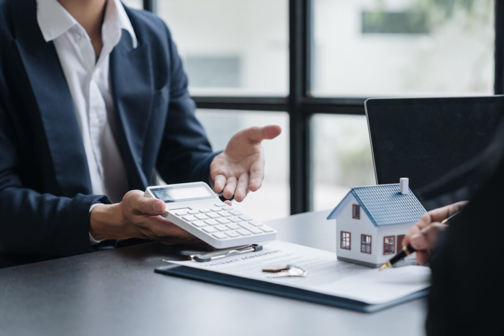 Real estate consultation with calculator and house.