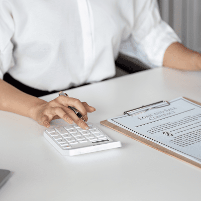 Person using calculator near loan agreement clipboard.