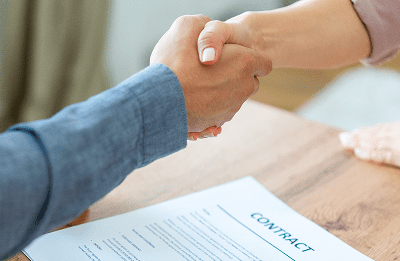 Handshake over a contract on a table.