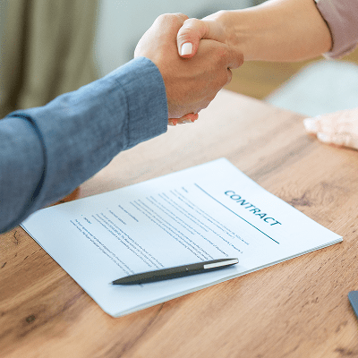 Handshake over a contract on a table.